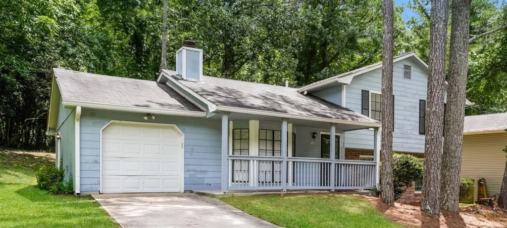 Split-level residence featuring a light blue exterior siding, an attached single-car garage, and a welcoming front porch with a white railing