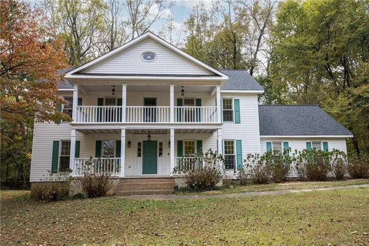 Two-story Colonial-style residence featuring white siding, a full-width two-story porch, teal shutters, and a dark shingle roof
