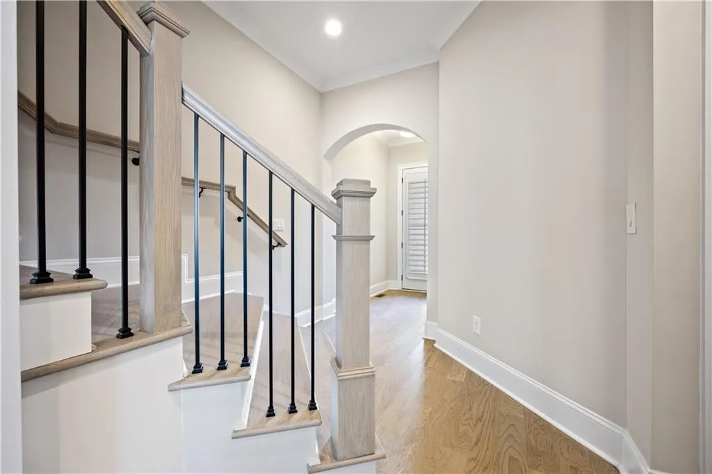 Stairway with baseboards, ornamental molding, wood finished floors, recessed lighting, and arched walkways