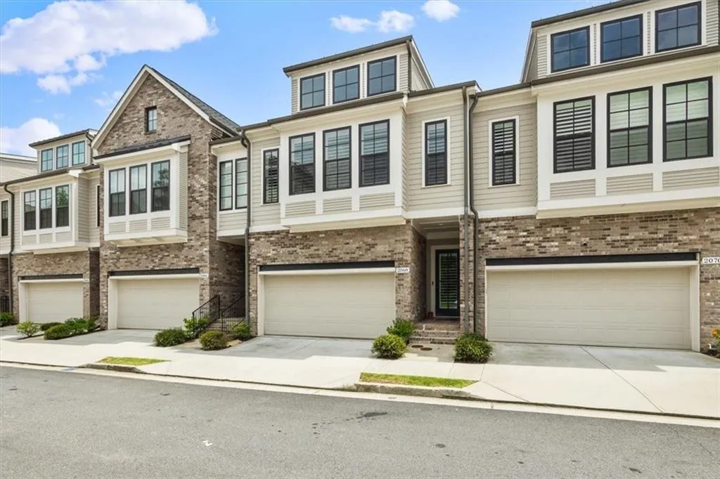 View of property featuring an attached garage and brick siding