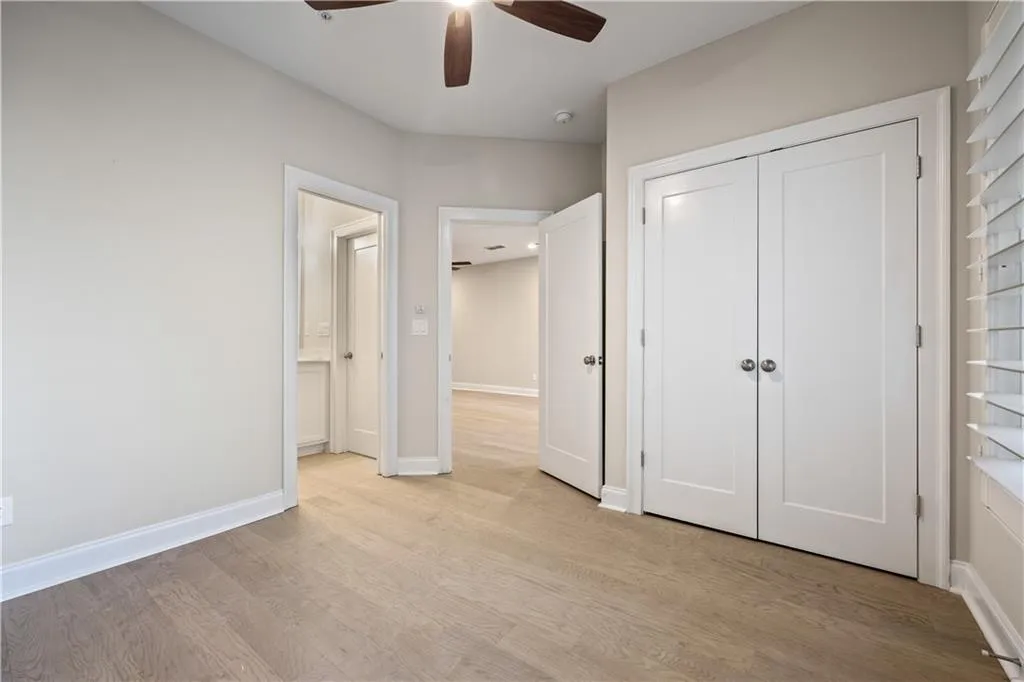 bedroom with baseboards, light wood-type flooring, a closet, and a ceiling fan