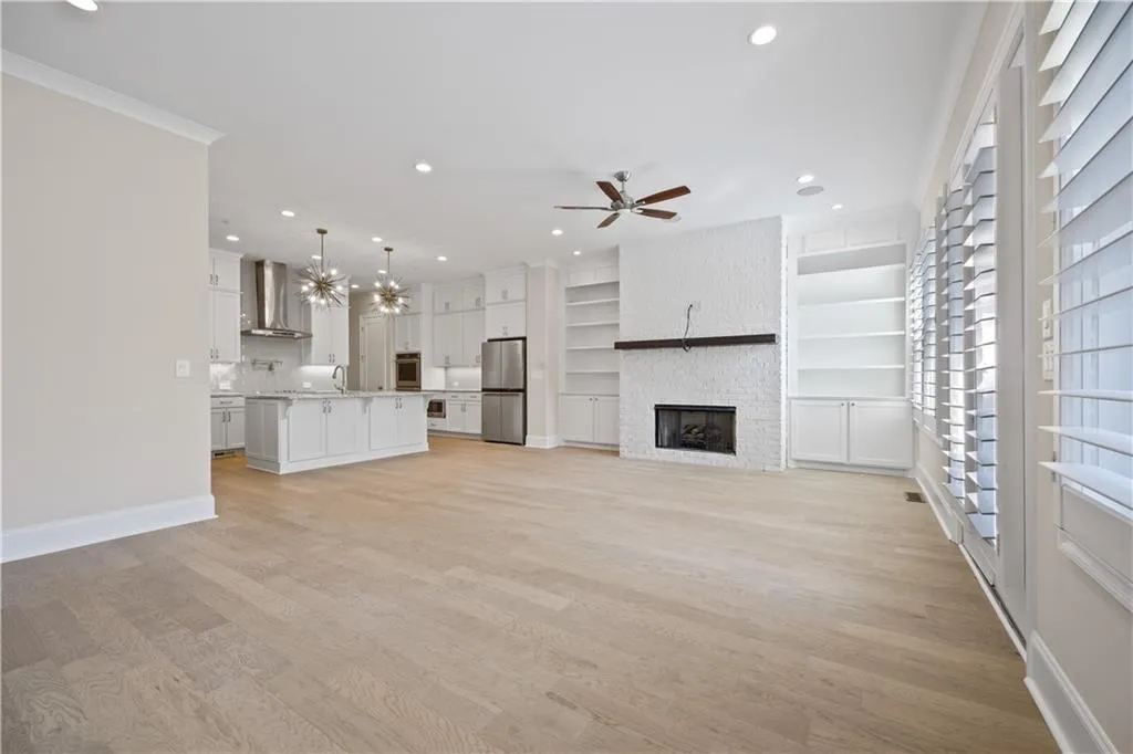 Unfurnished living room with a large fireplace, a ceiling fan, light wood-style flooring, and recessed lighting