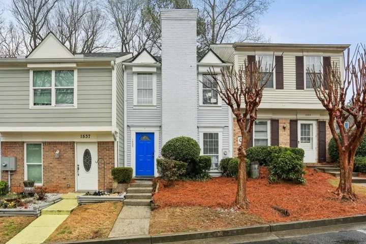 Multi-level townhouse exterior featuring a prominent white brick chimney