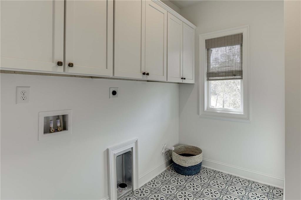Lovely Utility Room with upgrade tile flooring and cabinets for storage.