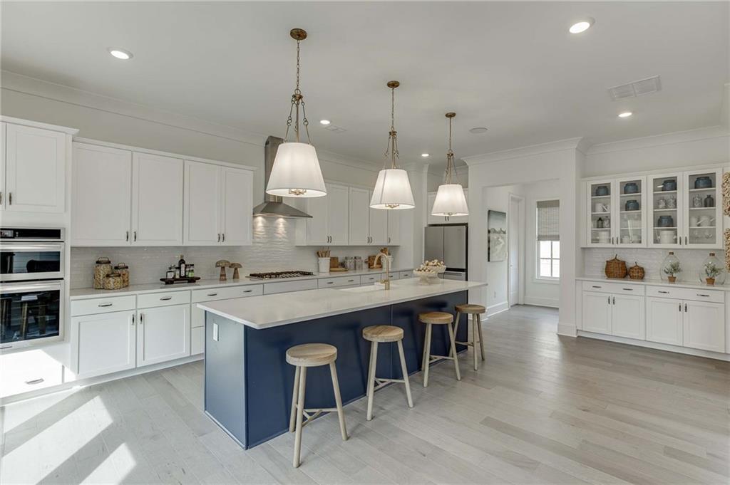 White cabinetry in kitchen with navy island.