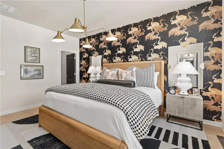 Accent wall featuring a patterned wallpaper, light wood-finish flooring, and a modern gold-tone multi-arm ceiling light fixture