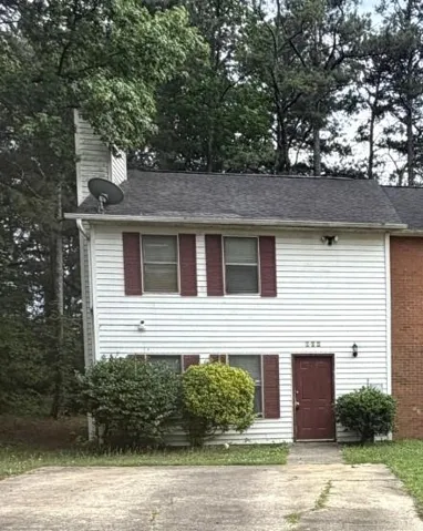 Two-story residential structure featuring white siding, a dark asphalt shingle roof, and a red front door