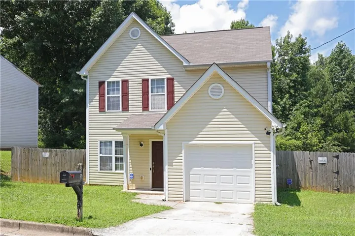 Traditional-style house featuring concrete driveway, a shingled roof, and an attached garage