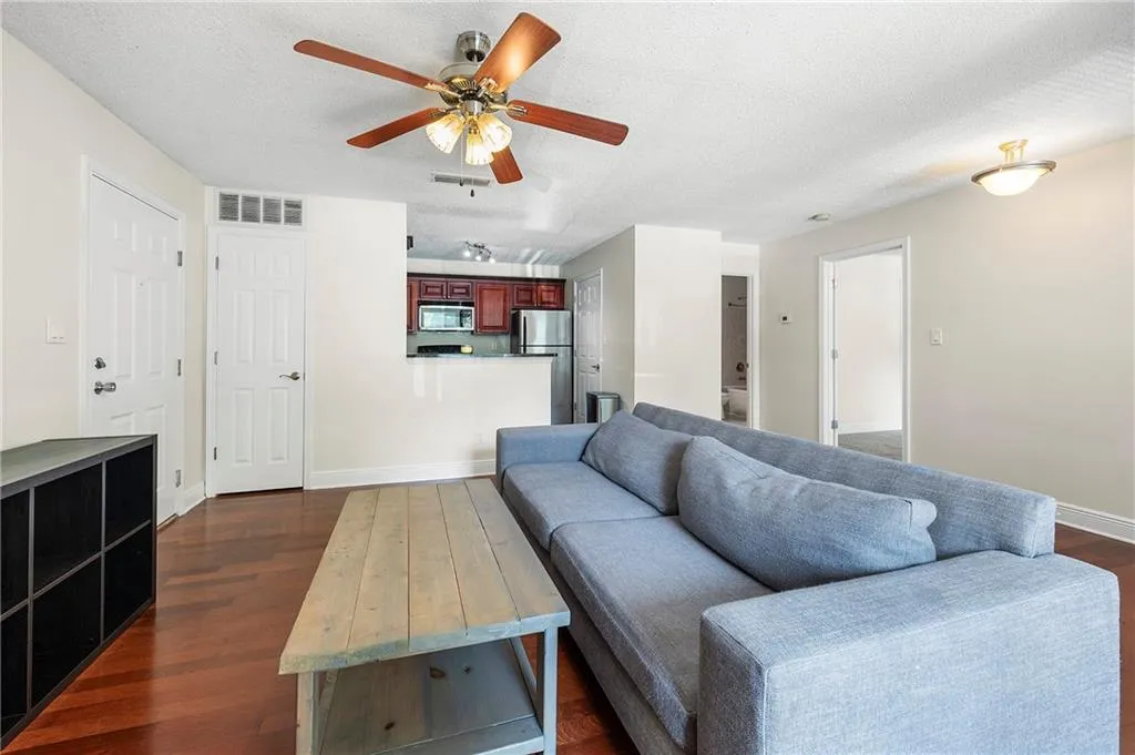Living area featuring a ceiling fan, dark wood-style floors, and a textured ceiling