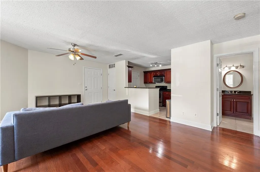 Living room featuring ceiling fan, light wood-style flooring, and a textured ceiling