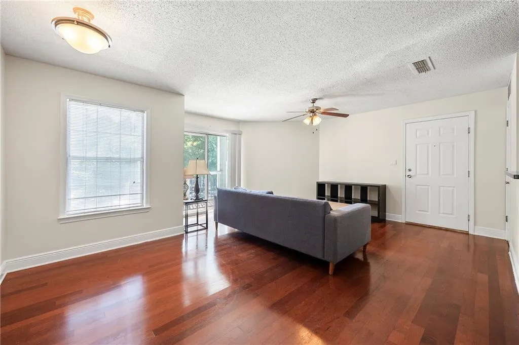 Living area with wood finished floors, a ceiling fan, and a textured ceiling