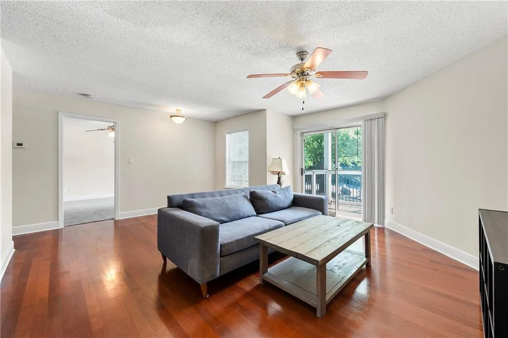 Living room featuring ceiling fan, a textured ceiling, and wood finished floors