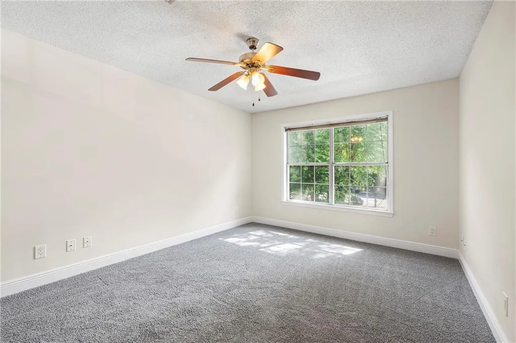 Empty room with a textured ceiling, ceiling fan, and carpet