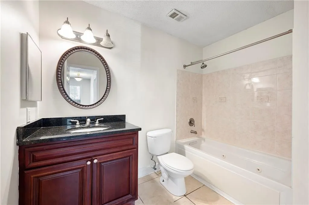 Full bathroom featuring a combined bath / shower with jetted tub, tile patterned flooring, vanity, and a textured ceiling