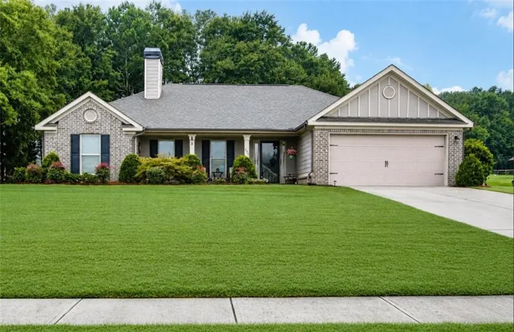 Brick and siding exterior with a gabled roofline, attached two-car garage, covered entry with columns, and a concrete driveway