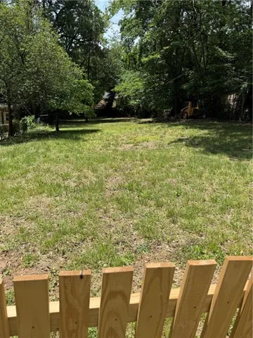 Expansive grassy yard area framed by a newly constructed wooden fence in the foreground
