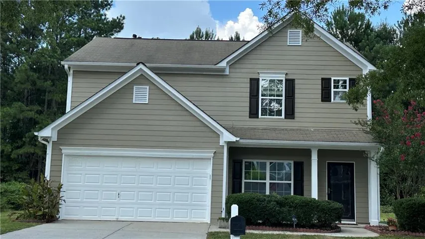 Two-story residence featuring light siding, an attached garage, a covered entry, and dark window shutters