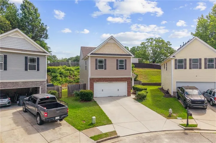 Two-story residence featuring a two-car garage, concrete driveway, and a front yard with manicured shrubs