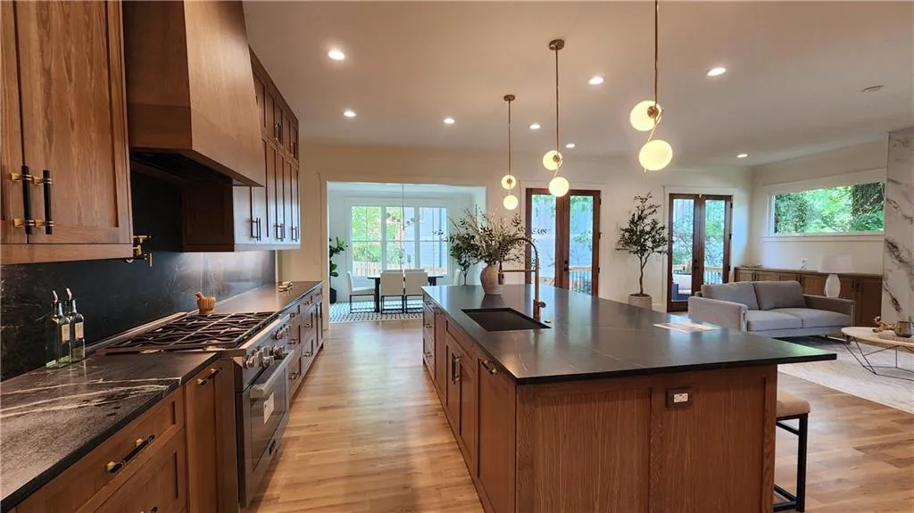 Kitchen with high end stainless steel range oven, light wood-type flooring, a kitchen bar, brown cabinets, and recessed lighting