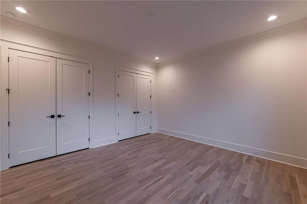 Unfurnished bedroom featuring two closets, recessed lighting, wood finished floors, and ornamental molding