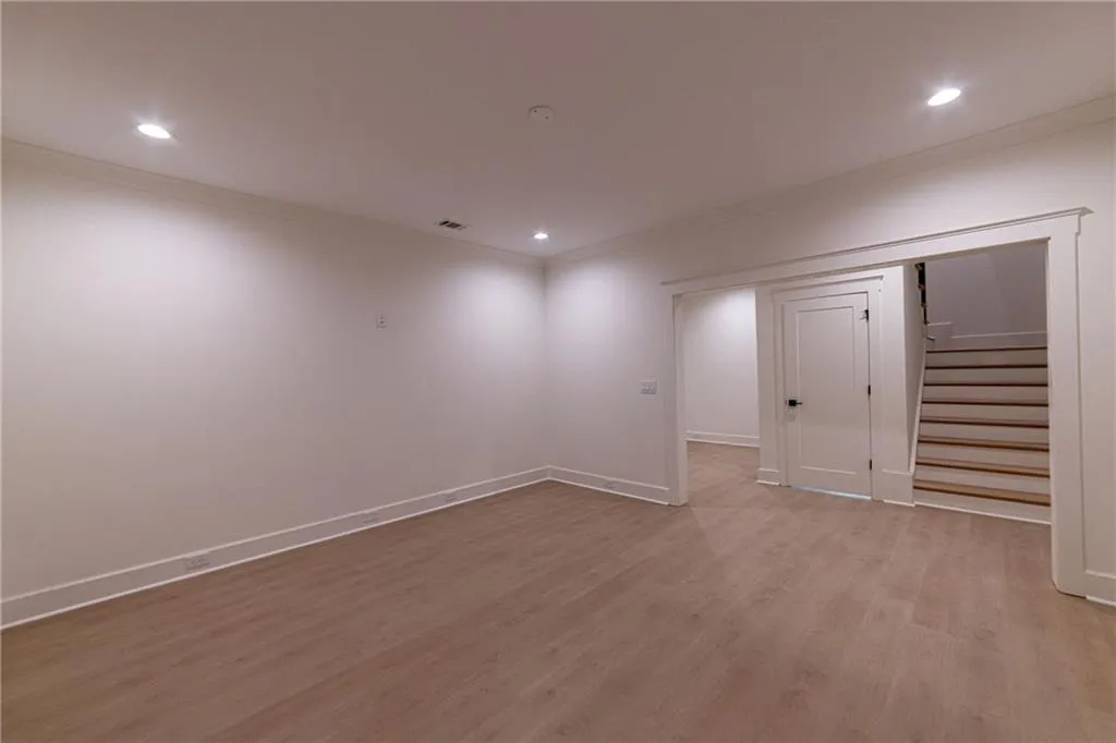 Finished below grade area featuring stairs, light wood finished floors, recessed lighting, and crown molding