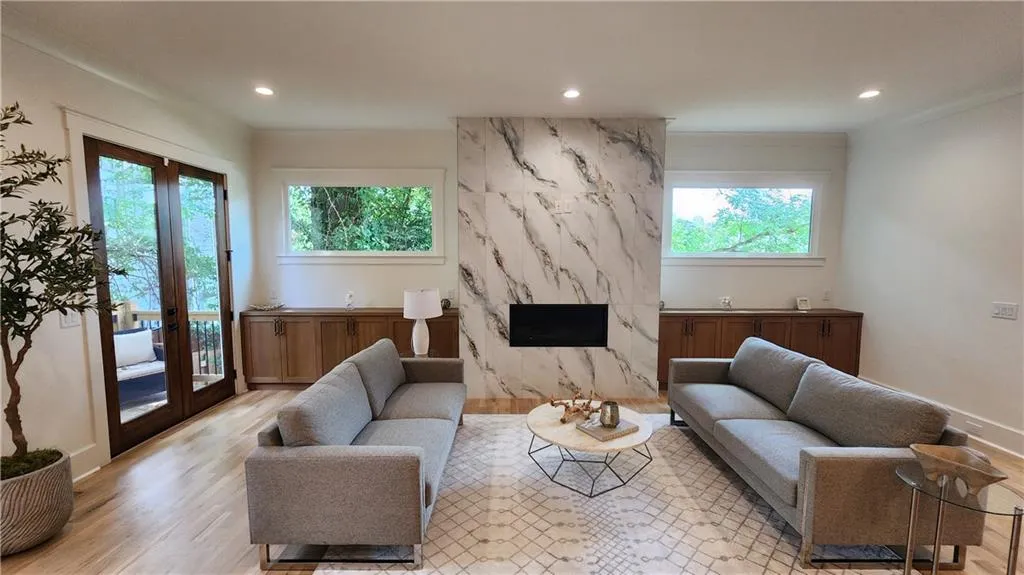 Living room with a fireplace, recessed lighting, light wood-style floors, french doors, and ornamental molding