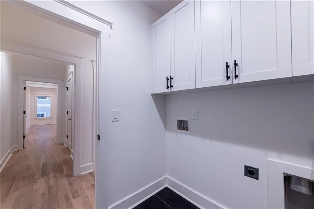 Laundry area with electric dryer hookup, cabinet space, hookup for a washing machine, and light wood finished floors