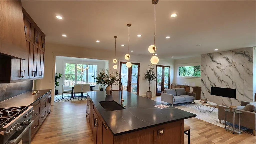 Kitchen with dark countertops, high end stove, open floor plan, plenty of natural light, and recessed lighting