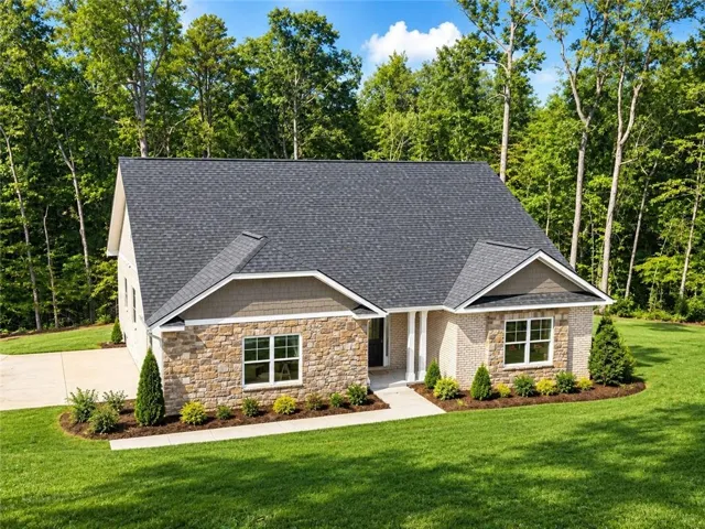 Contemporary-style architecture with a dark shingle roof and a combination of stone and brick veneer siding