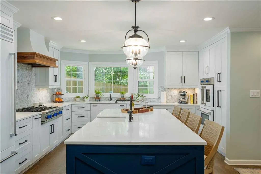 Kitchen featuring decorative light fixtures, backsplash, custom exhaust hood, white cabinets, and dark hardwood / wood-style flooring
