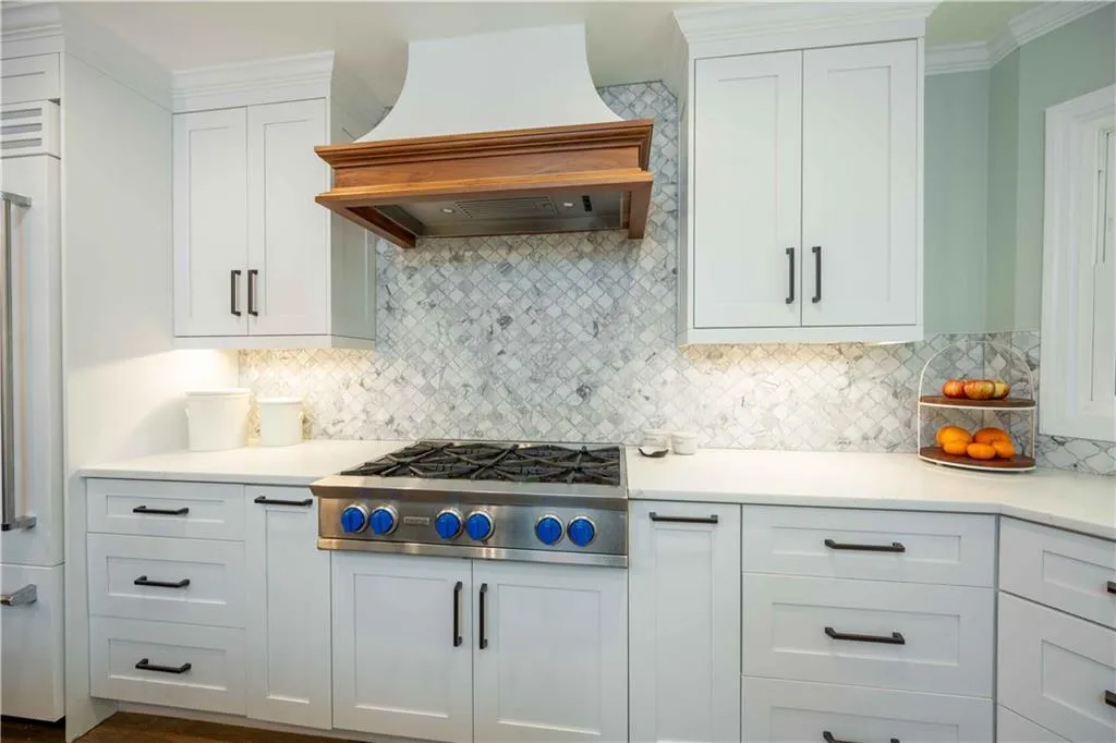 Kitchen featuring white cabinetry, custom range hood, backsplash, and stainless steel gas cooktop