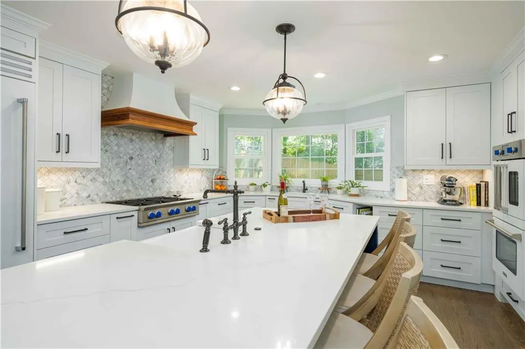 Kitchen featuring decorative light fixtures, tasteful backsplash, white cabinetry, dark hardwood / wood-style floors, and custom range hood