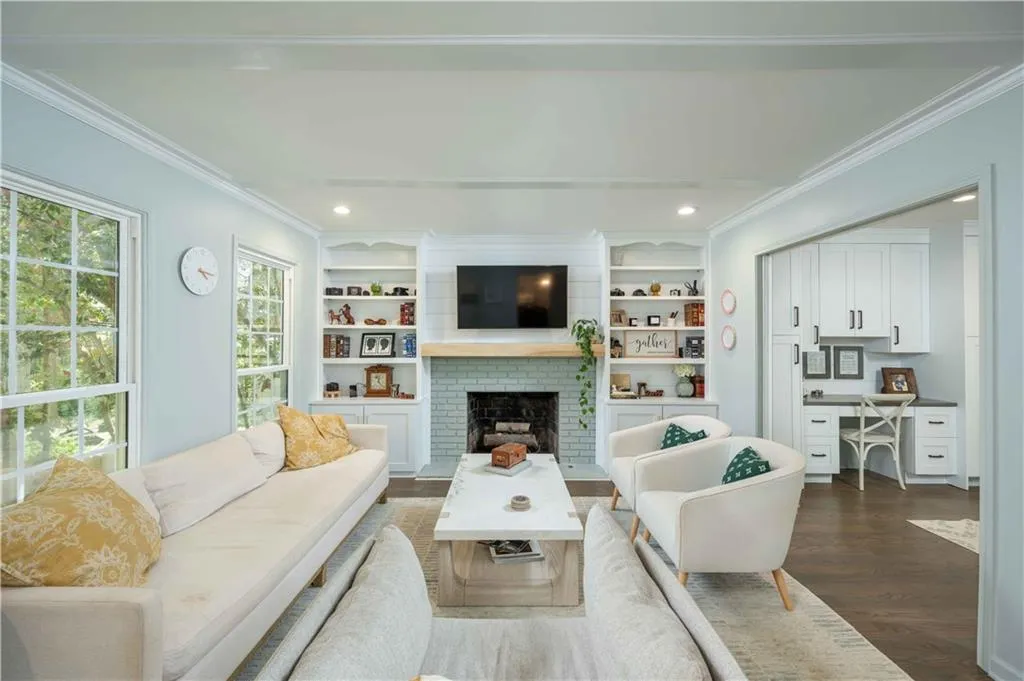 Living room featuring dark hardwood / wood-style floors, a brick fireplace, built in features, and ornamental molding