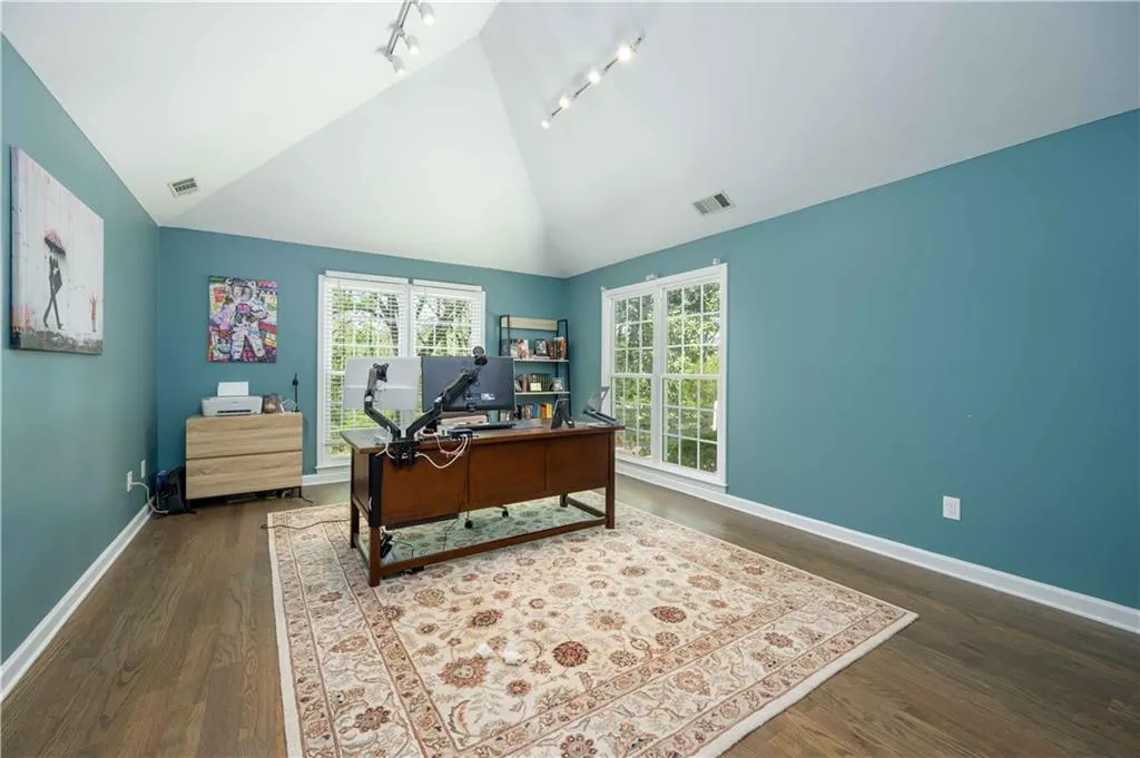 Home office featuring rail lighting, a healthy amount of sunlight, and dark hardwood / wood-style floors