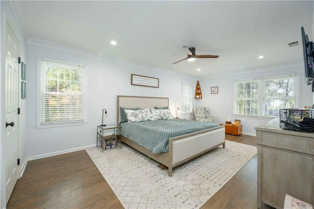 Bedroom with hardwood / wood-style floors, ornamental molding, and ceiling fan