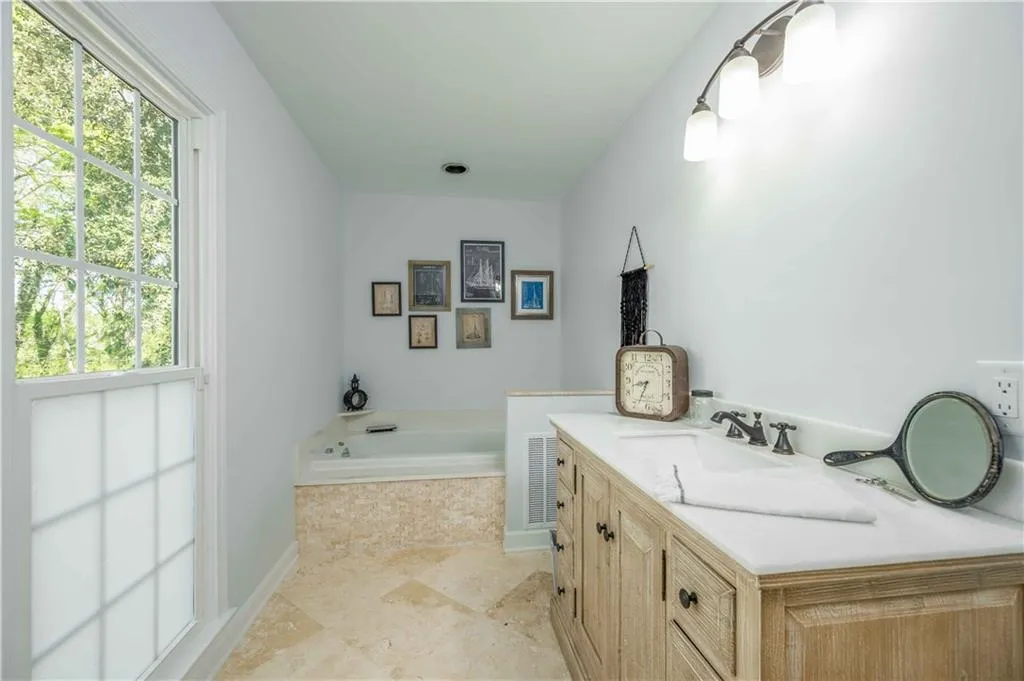 Bathroom with plenty of natural light, tiled tub, tile floors, and vanity