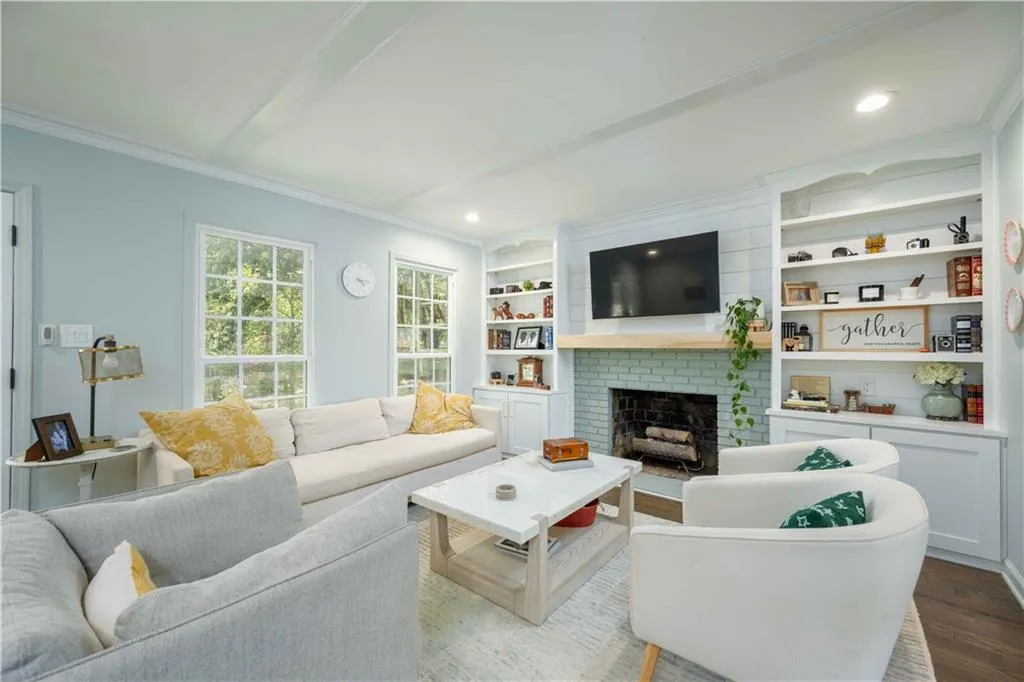 Living room with built in features, hardwood / wood-style floors, crown molding, and a fireplace