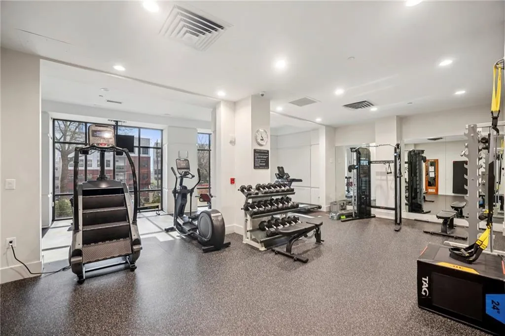 Fitness center featuring rubber flooring, recessed lighting, expansive windows, a full mirrored wall, and a comprehensive selection of exercise equipment