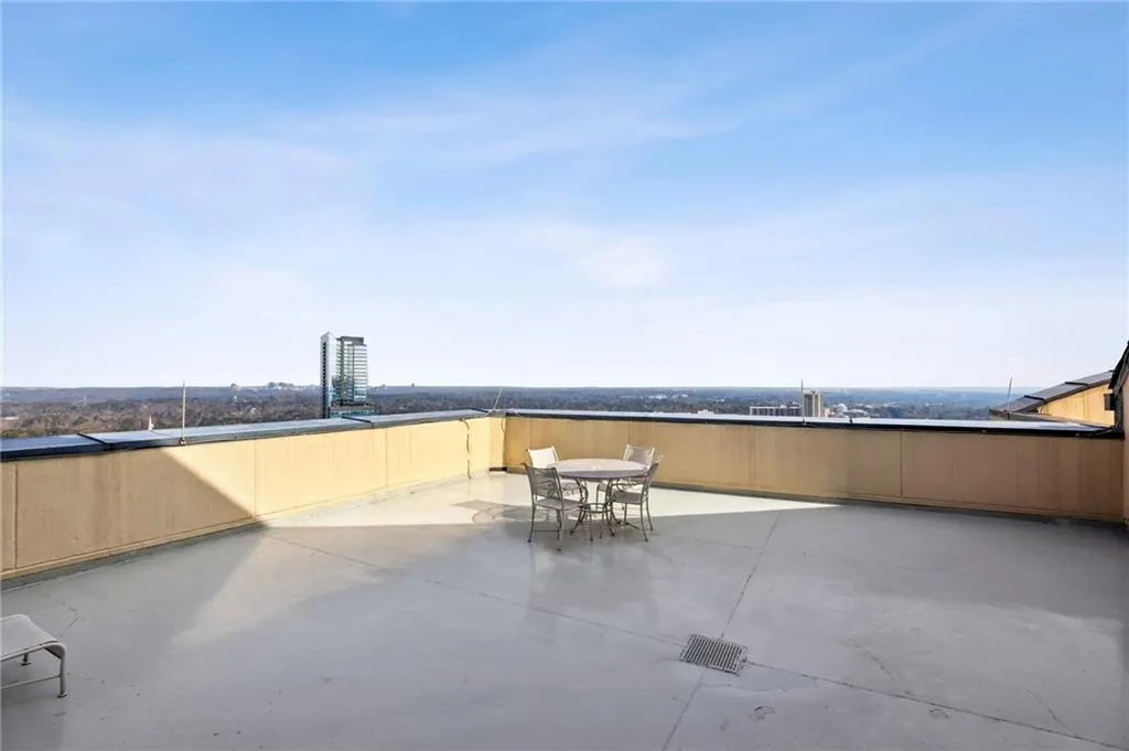 Expansive rooftop terrace with a light-colored paved surface, featuring a low perimeter wall