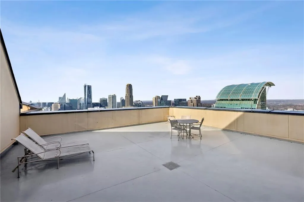 Expansive rooftop terrace featuring a smooth, light-colored surface and a substantial perimeter wall