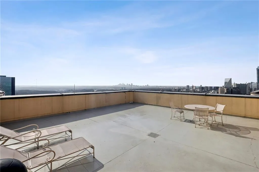 Expansive rooftop terrace with a concrete surface and a partial perimeter wall