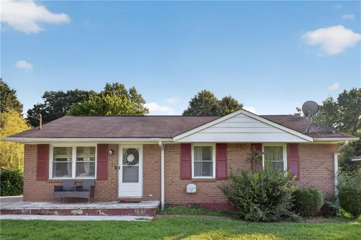Brick exterior, white front door, red shutters, front porch, dark shingle roof