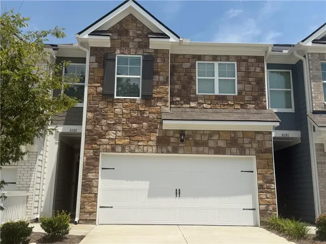 Stone veneer facade with a two-car garage featuring decorative hardware