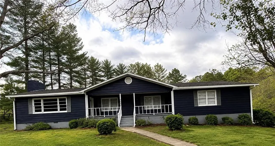Exterior featuring dark blue siding, a covered front porch, white railings, and a concrete walkway