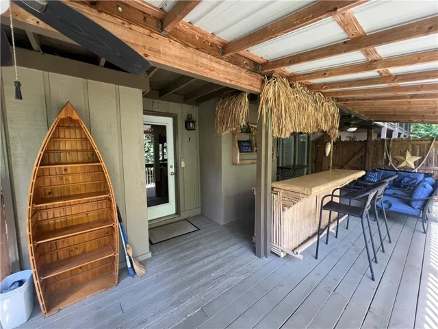 Covered outdoor patio featuring a slatted wood ceiling, built-in bar, and gray wood-finish decking