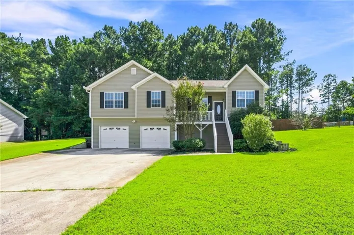 Two-car garage with individual doors, established landscaping, and a broad front lawn