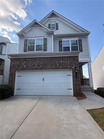 Two-story residence featuring brick and siding exterior, a two-car garage, concrete driveway, and a covered entry
