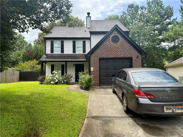 Two-story residence featuring a brick and white siding exterior, a dark shingled roof, and a single-car garage with a dark panel door