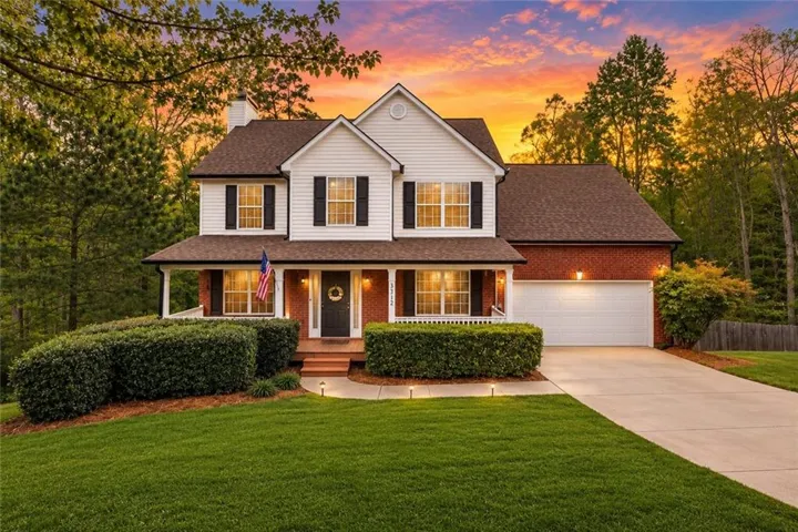 Traditional-style home featuring a covered front porch, brick and siding facade, and attached two-car garage