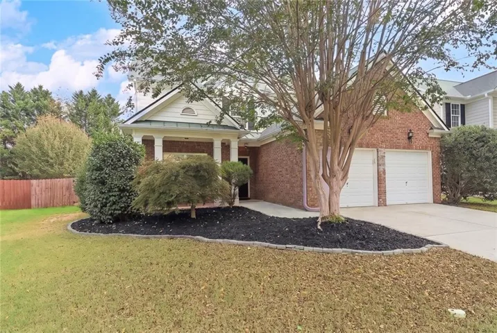 Brick exterior with a covered porch entry, dual garage doors, and a concrete driveway
